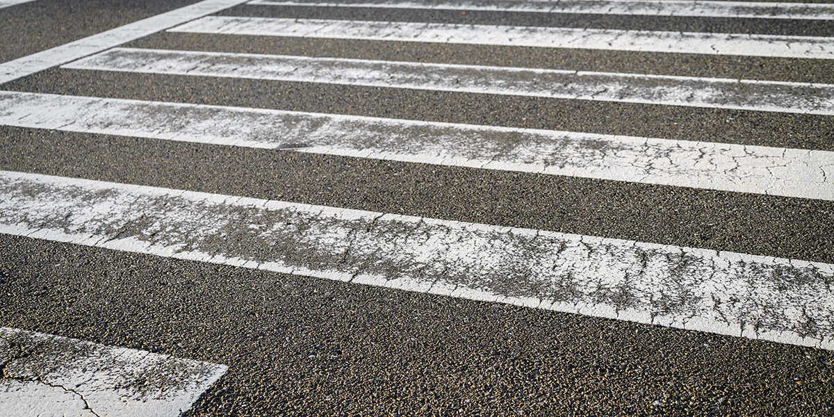 Close up of asphalt road with aging and faded stripes... The Importance of Asphalt Parking Lot Striping